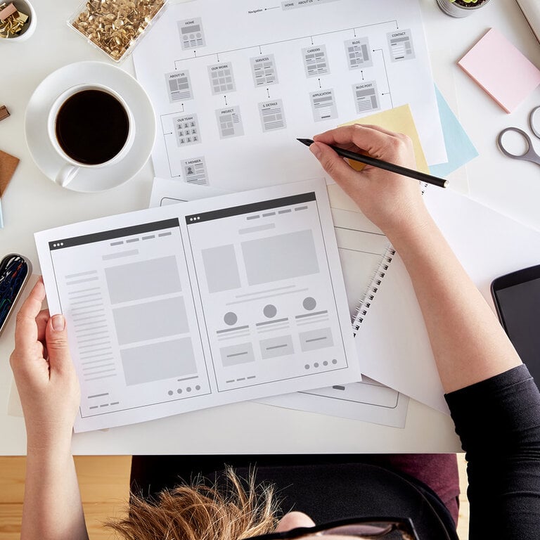 Designer sketching a website sitemap and wireframes on paper