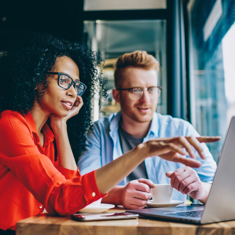 Woman and man discussing content on a laptop over coffee