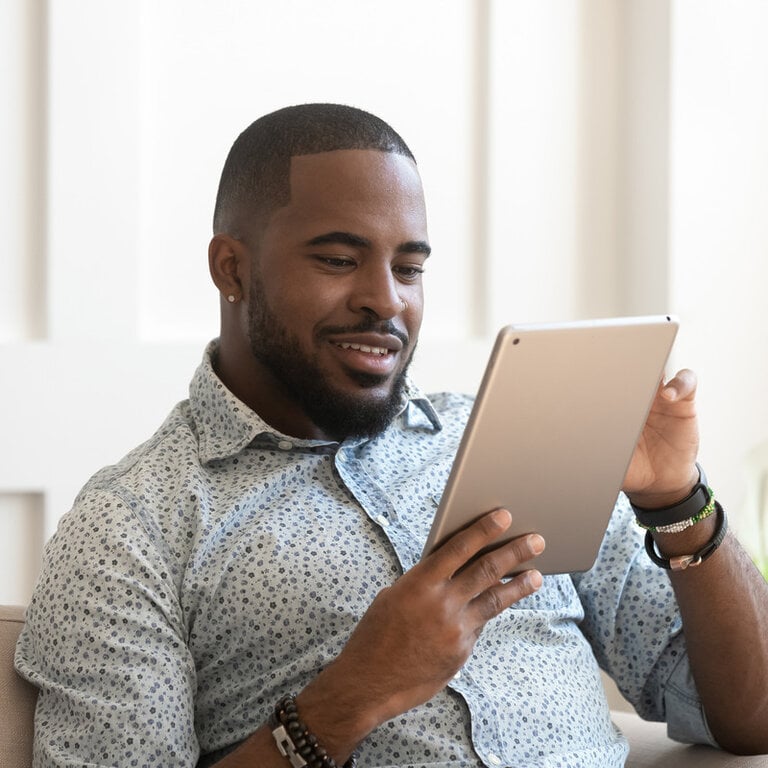 Man comfortably reading digital content on a tablet at home