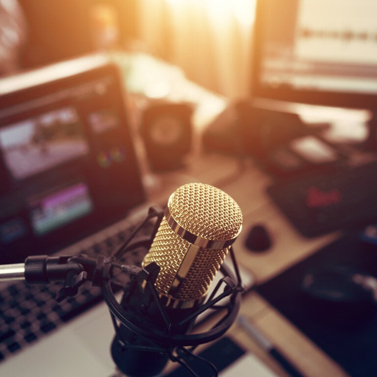 Studio microphone in front of a laptop set up for podcast recording