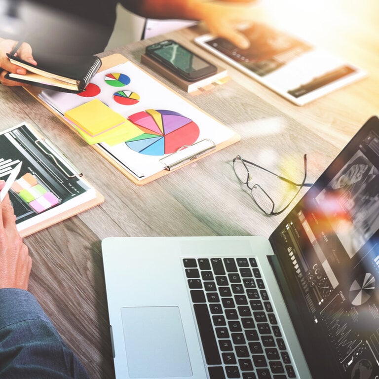 Marketer reviewing colorful pie charts and analytics on a laptop