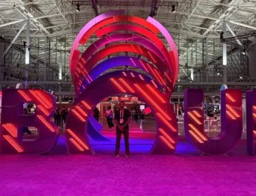 Adrian standing in front of the illuminated UNBOUND sign in a large convention hall