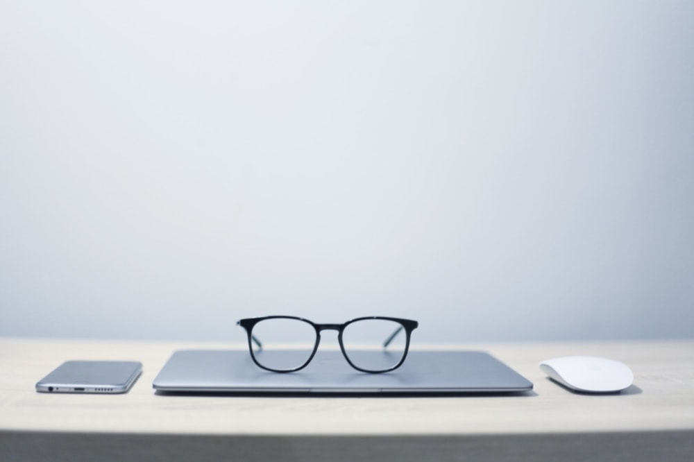 glasses sitting on laptop question with smartphone and mouse on table