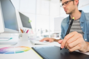 Man holding stylus looking at monitor