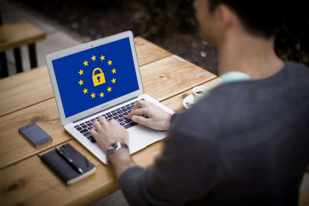 man using a notebook computer with a graphic of a lock on the screen to denote security