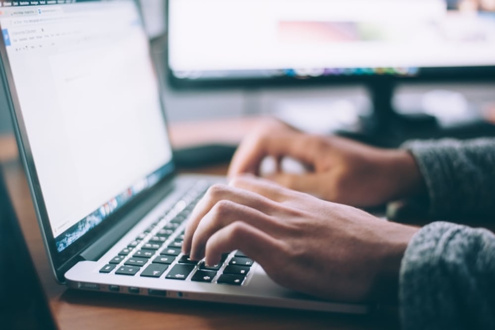 man typing on laptop computer